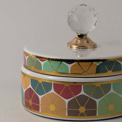 Closeup of vibrant ceramic jar showing fine geometric floral details and elegant crystal knob with gold base.