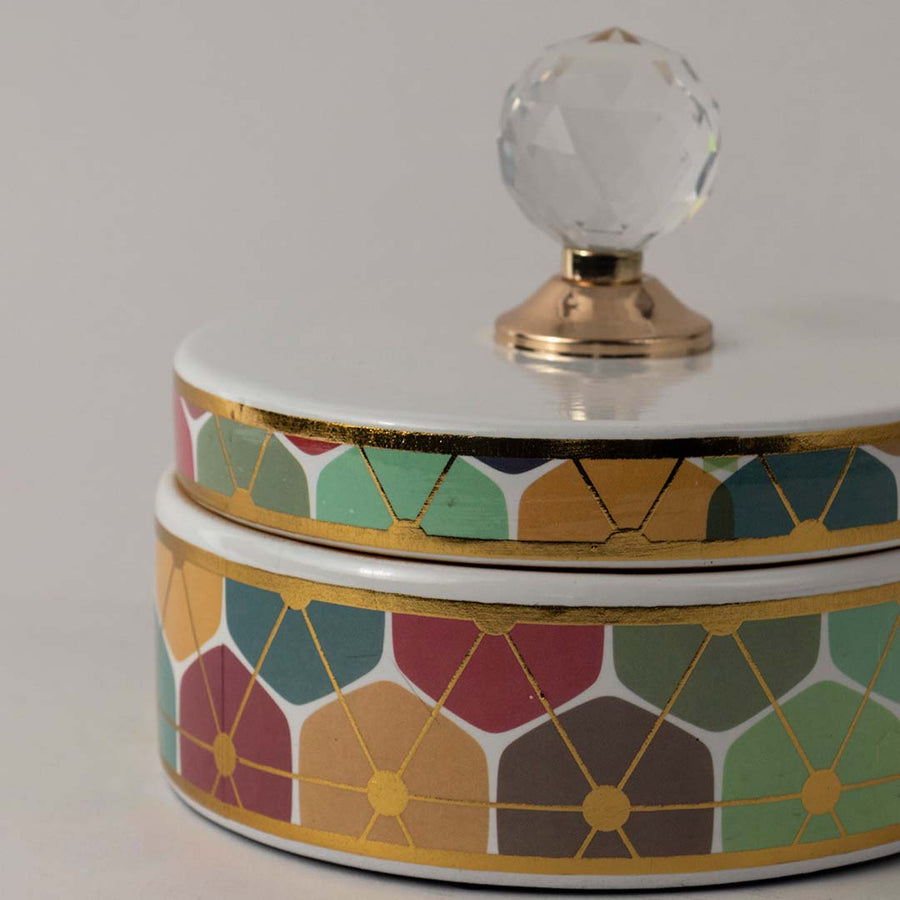 Closeup of vibrant ceramic jar showing fine geometric floral details and elegant crystal knob with gold base.
