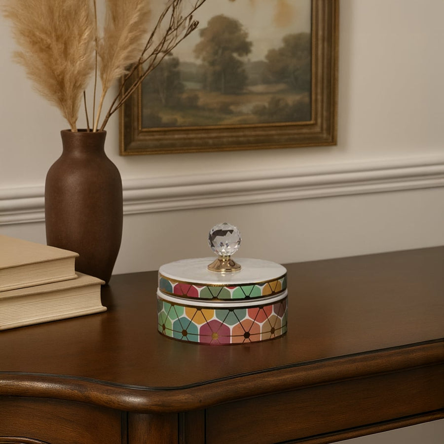 Small multicolor geometric ceramic jar with crystal knob lid styled on table adding artistic touch to home decor.