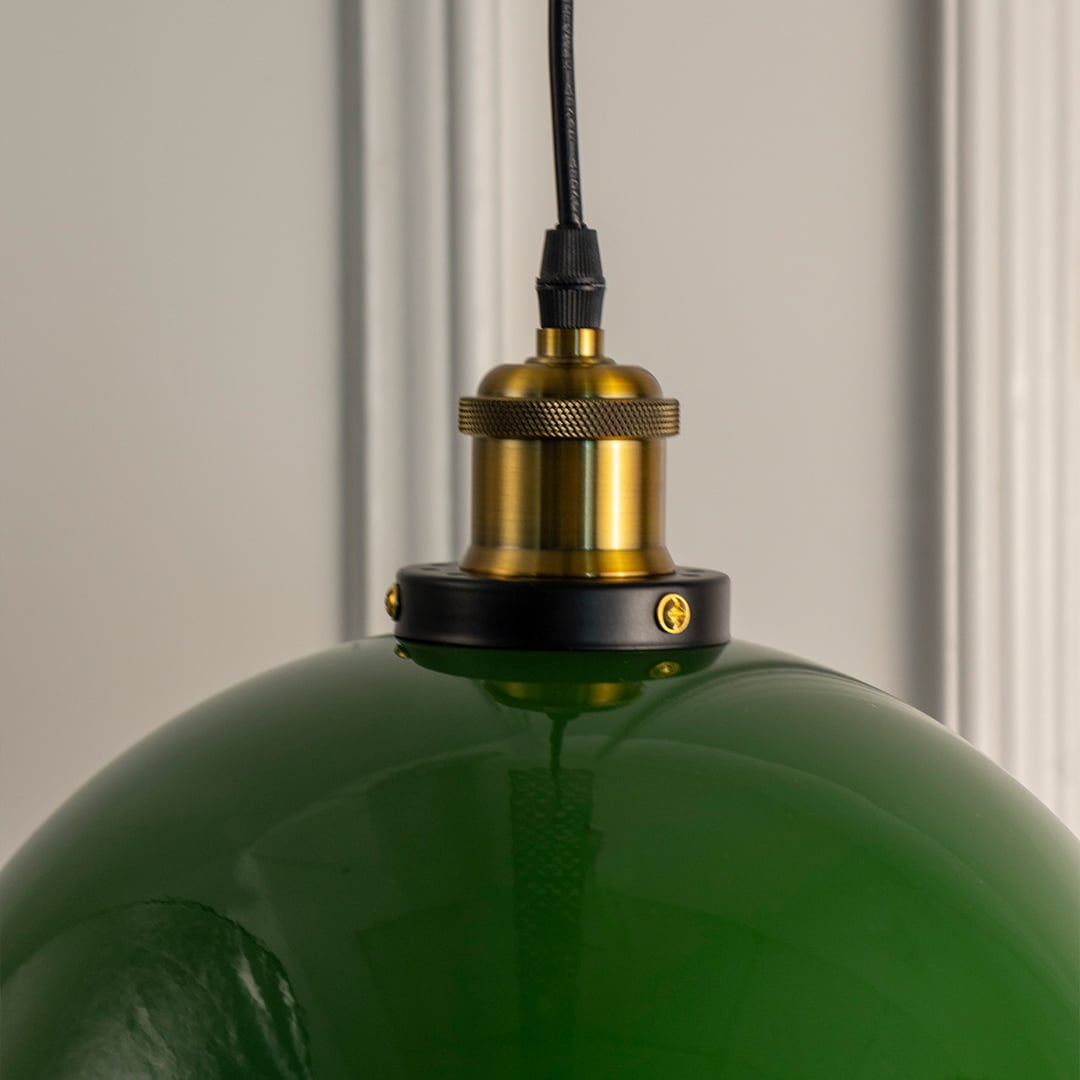 Closeup of glossy green dome hanging lamp highlighting smooth finish and brass fitting for modern home lighting.