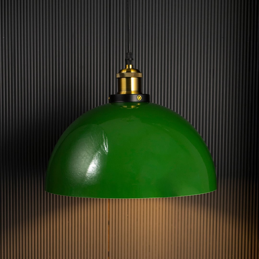 Green dome pendant lamp glowing warmly on black background adding cozy and sophisticated ambience to interiors.