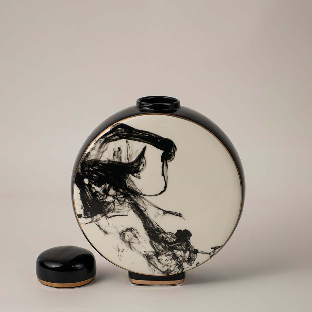 Contemporary round black and white ceramic vase with artistic abstract design placed on white background for home decor.