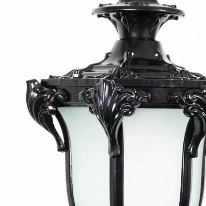 Closeup of black hanging lantern light showing fine detailing with frosted glass panels and curved metal frame.
