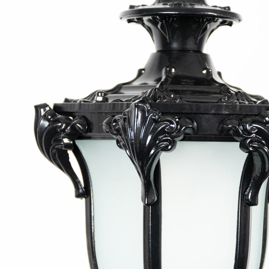 Closeup of black hanging lantern light showing fine detailing with frosted glass panels and curved metal frame.