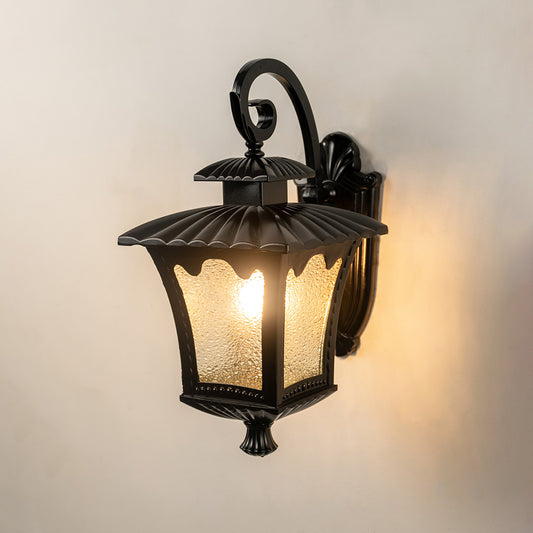 Black metal outdoor wall light on white background with frosted seeded glass shade for entry porch decor.