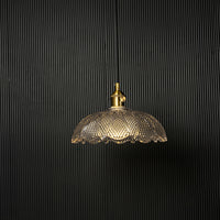 Clear patterned glass pendant light with gold metal accents designed for refined modern living spaces.