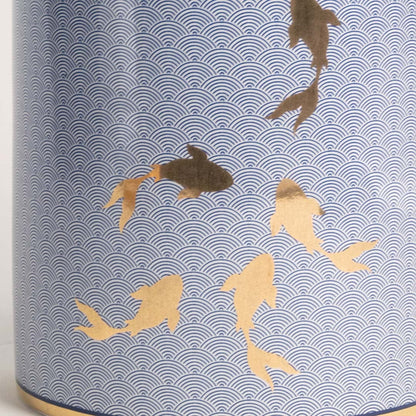 Closeup of blue ceramic jar with intricate golden fish design showcasing glossy finish and fine craftsmanship.