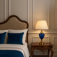 Blue glass table lamp with golden accents enhancing living room and bedside interiors with modern decor.