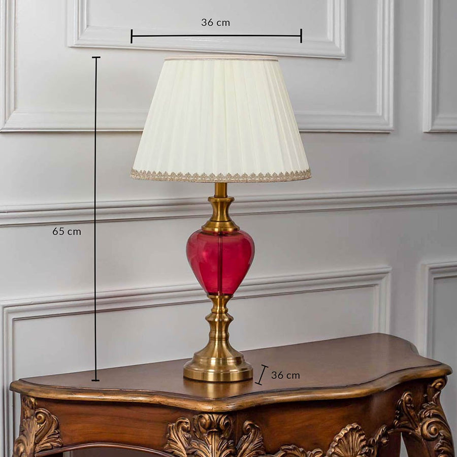 Red glass table lamp with pleated shade and golden accents shown with 65cm height and 36cm width.