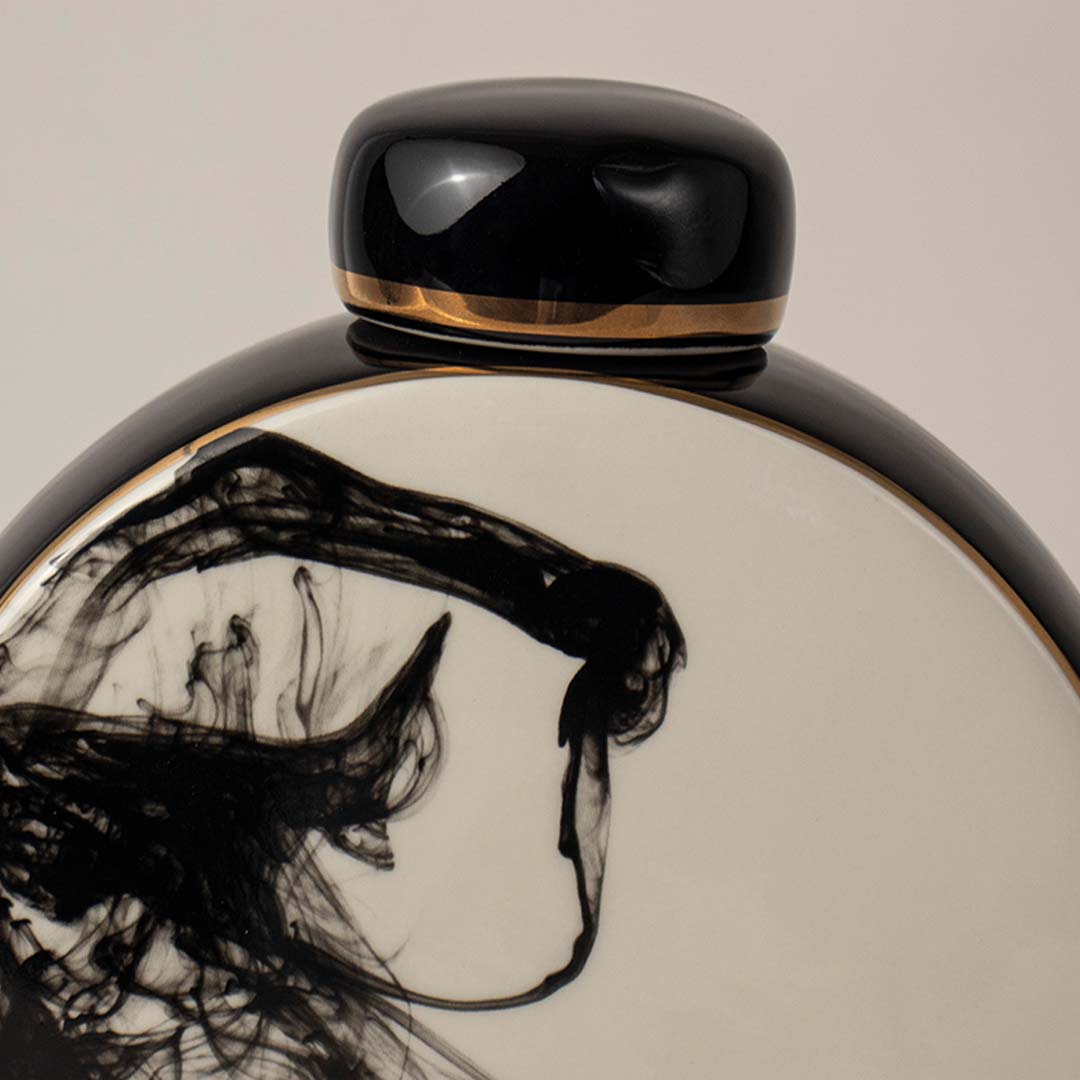 Closeup view of round ceramic vase in black and white tones highlighting detailed abstract ink pattern for table styling.