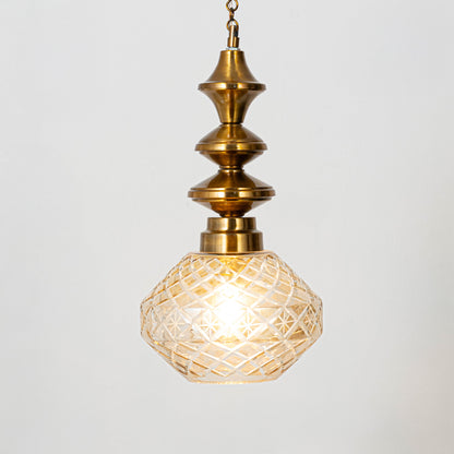 Elegant pendant light in gold metal finish with patterned glass shade for dining room or living decor lighting white background.