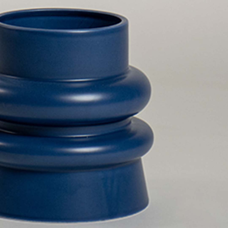 Closeup of deep blue ceramic vase showcasing its smooth matte finish and sculpted round contours ideal for decorative styling.