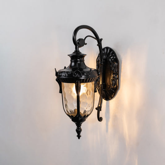 Glossy black metal outdoor wall light on white background with clear water glass shade casting reflections for decor.