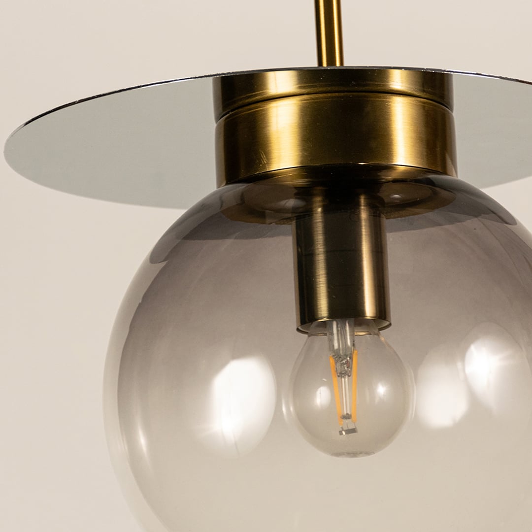 Close view of smoked glass pendant light showing transparent gradient finish golden holder and modern minimal craftsmanship.