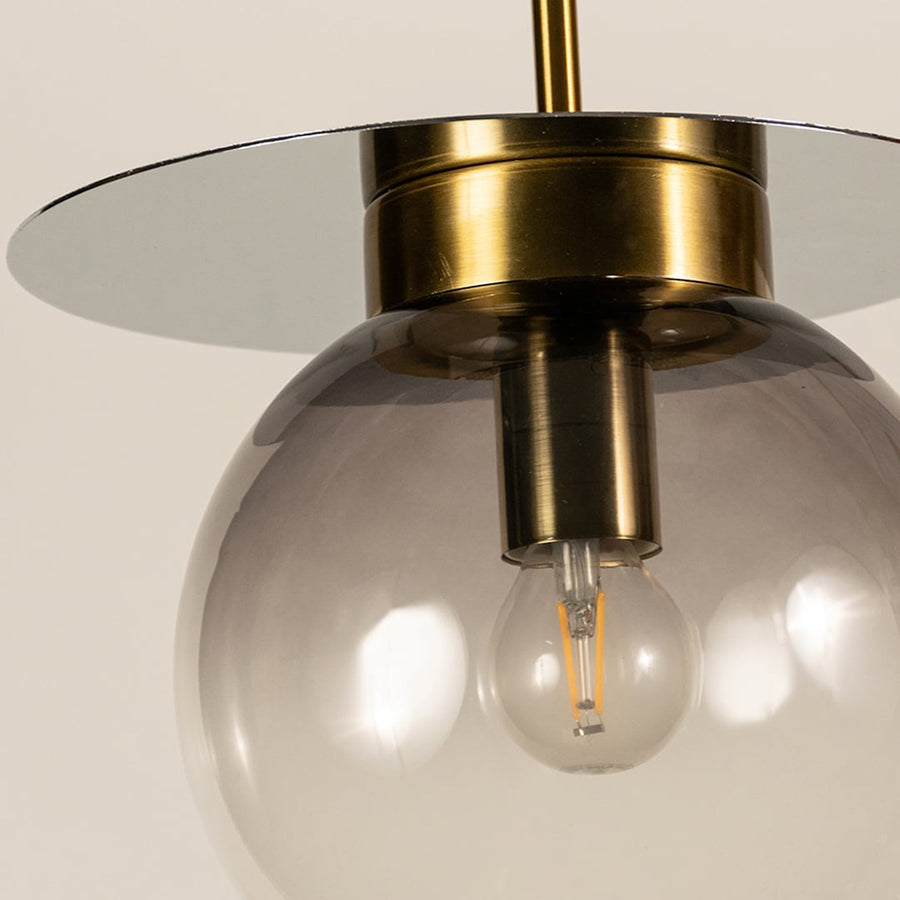 Close view of smoked glass pendant light showing transparent gradient finish golden holder and modern minimal craftsmanship.