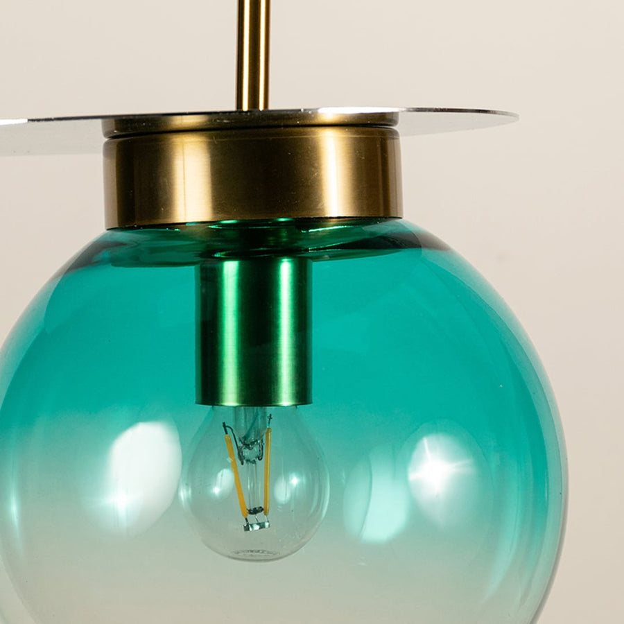 Close view of blue glass pendant hanging light showing smooth gradient finish polished gold holder and refined artistic details.