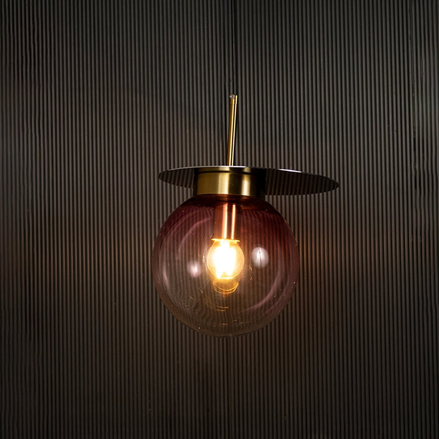 Elegant pink glass pendant light illuminated beautifully on dark background highlighting modern craftsmanship and soft warm glow.