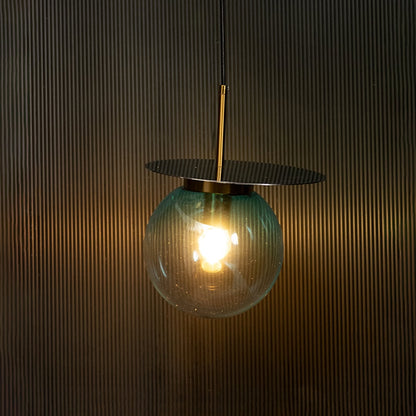 Elegant blue and white glass pendant light illuminated on dark background highlighting artistic craftsmanship and sophisticated modern design.