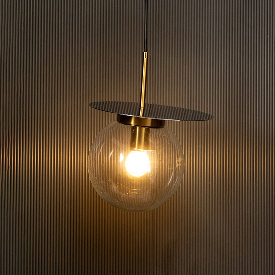 Elegant glass globe pendant light illuminated on dark background highlighting its sophisticated design and warm decorative glow.