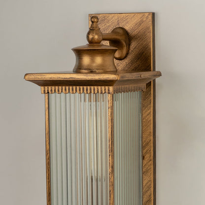 Antique brass metal outdoor wall light closeup image showing premium textured finish and linear fluted glass details.