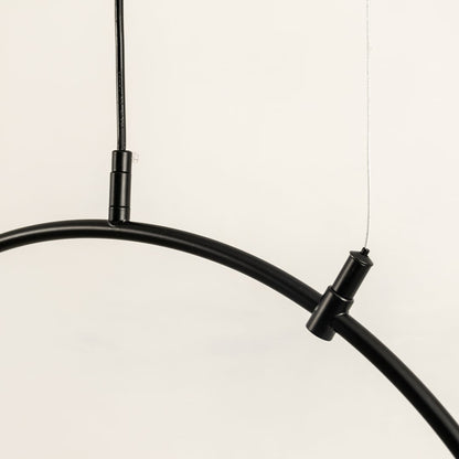 Close up of a black curved ceiling light frame with two slim hanging wires attached shown against a light background.