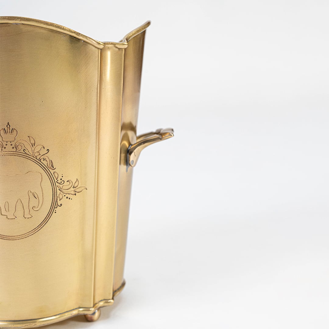 Detailed closeup view of the etched elephant logo and decorative scalloped rim design on the polished gold brass bucket surface.