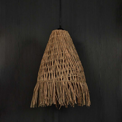 Rattan pendant light with tall woven shade and fringed edge shown off on black background for rustic home decor.