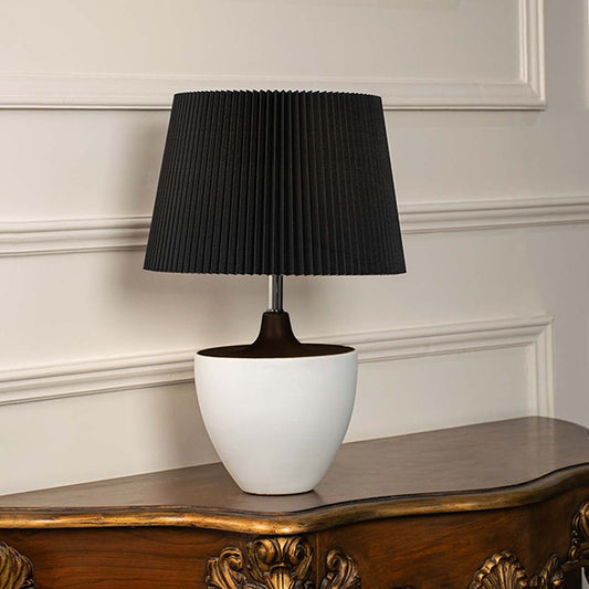 Black pleated shade table lamp with white ceramic base and dark metal stem for modern luxury interior styling.