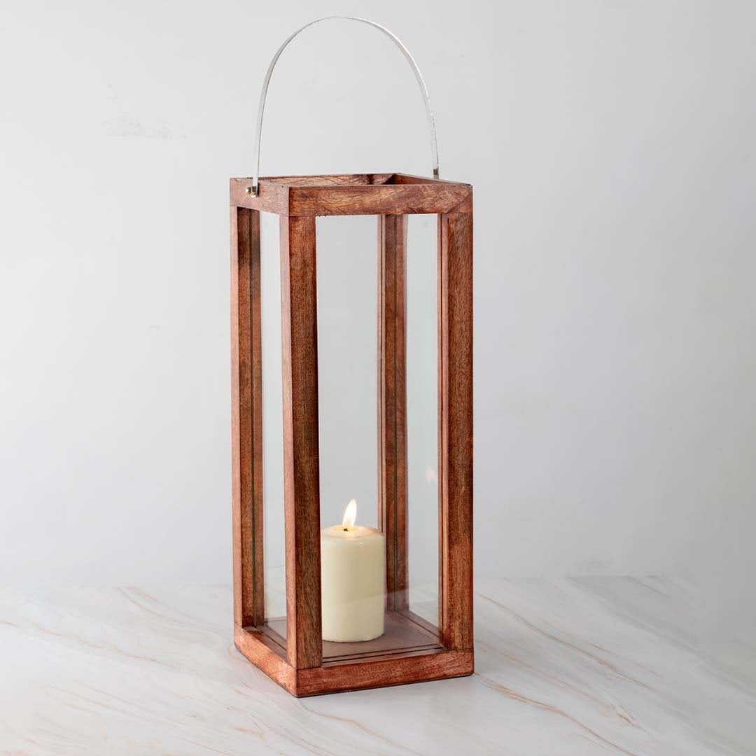 Handcrafted wooden lantern with glass panels and a silver handle displayed on white background with candlelight inside highlighting the natural wood grain.