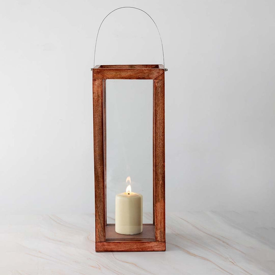 Handcrafted wooden lantern with glass panels and a silver handle displayed on white background with candlelight inside highlighting the natural wood grain.
