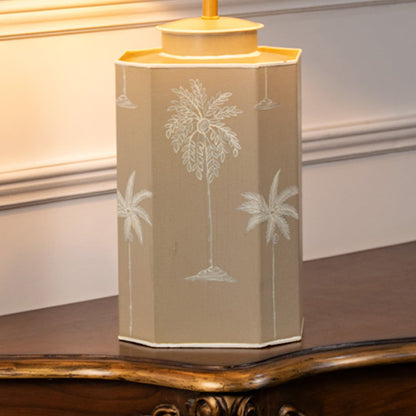 Table lamp closeup featuring beige ceramic base with subtle palm tree motif and soft matte finish.