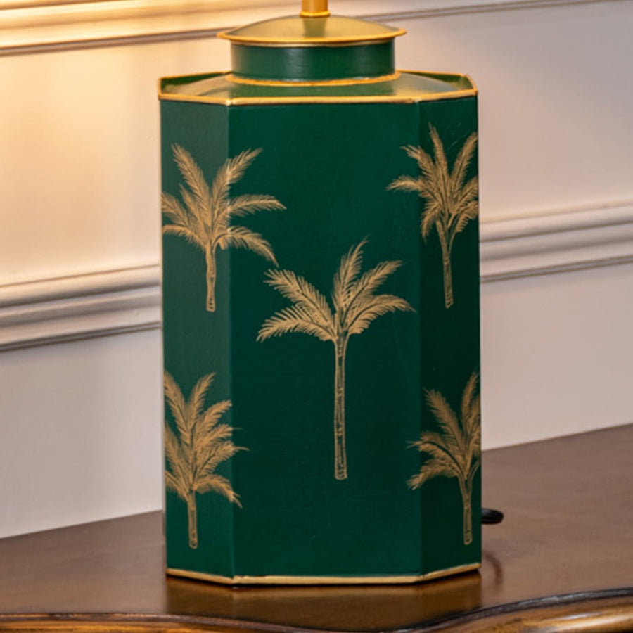 Table lamp closeup displaying green ceramic base with gold palm tree artwork and refined edges.