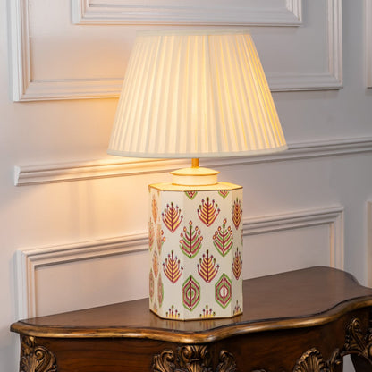 Table lamp on white background showcasing detailed patterned ceramic base paired with pleated fabric shade for refined decor styling.