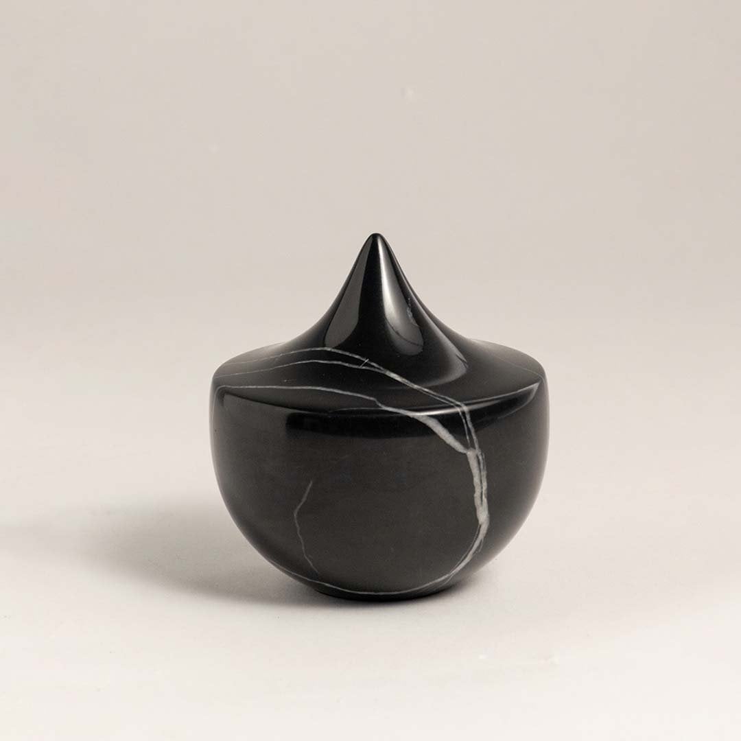 Black marble sculpture with a sharp peak displayed against a plain white background showcasing its sleek design.