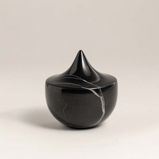 Black marble sculpture with a sharp peak displayed against a plain white background showcasing its sleek design.