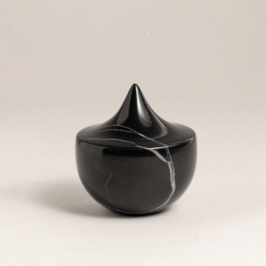 Black marble sculpture with a sharp peak displayed against a plain white background showcasing its sleek design.