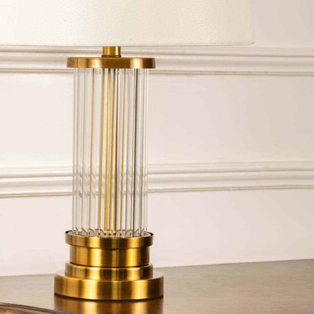 White shade gold rod base table lamp on wooden sideboard with light off and white panel wall for elegant modern décor.