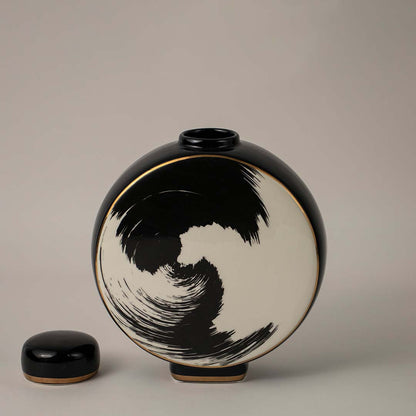 Round black and beige ceramic vase with swirl brush art design placed on white background for modern home styling.