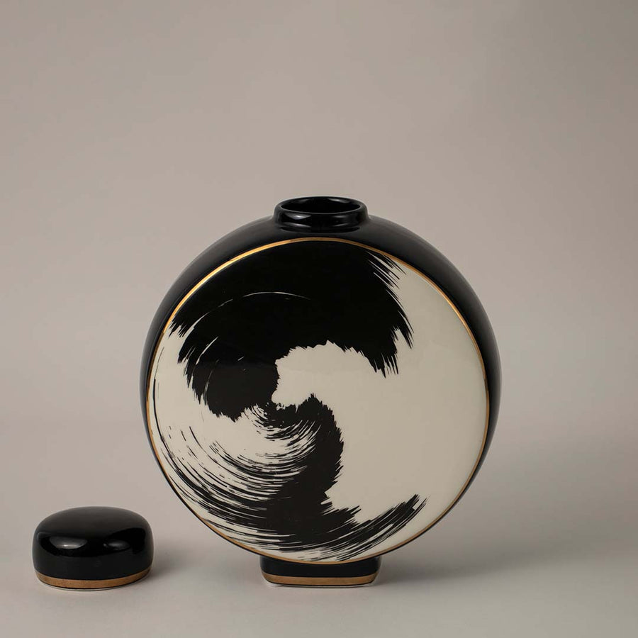 Round black and beige ceramic vase with swirl brush art design placed on white background for modern home styling.