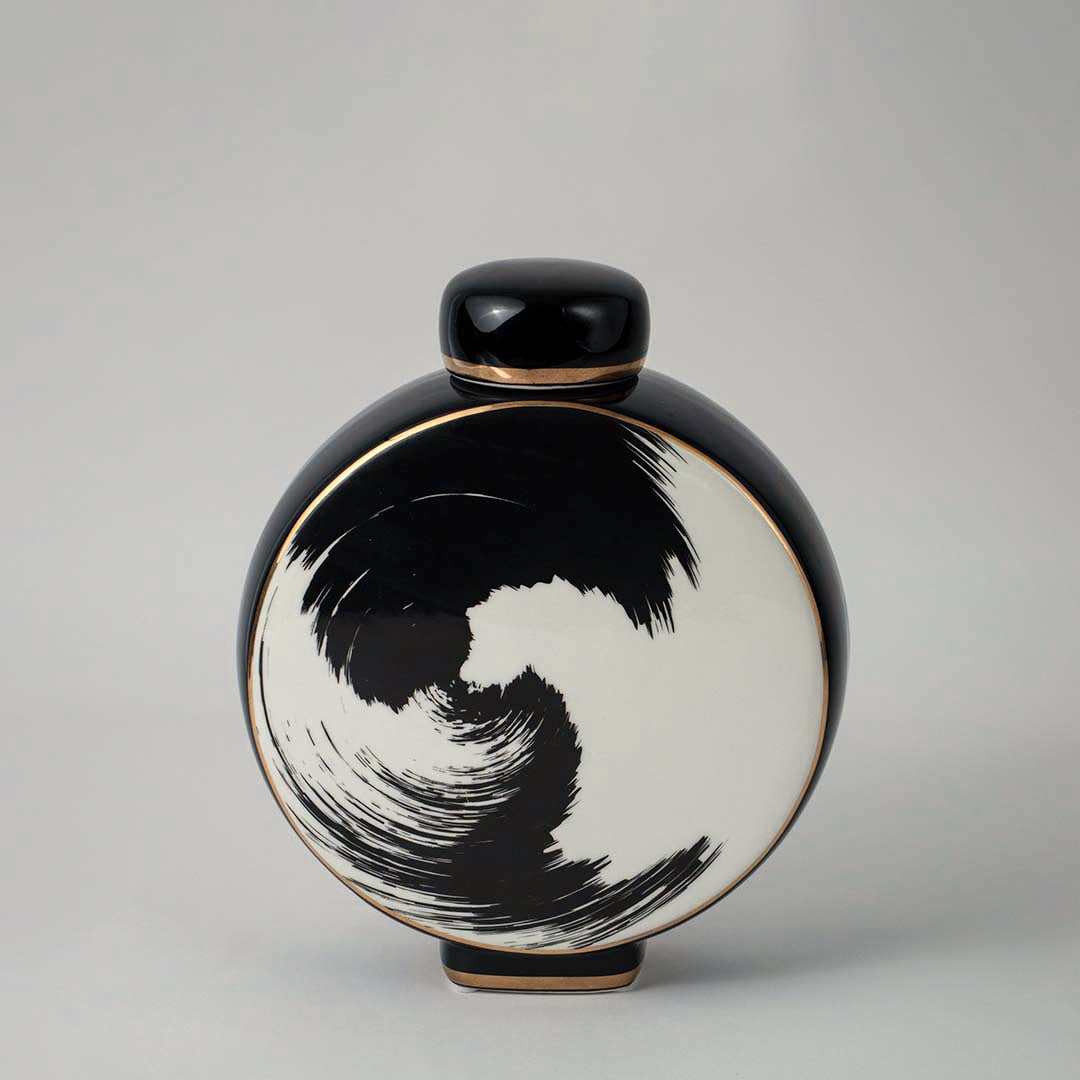 Round ceramic vase in black and beige tones with artistic swirl pattern displayed on white background for interior styling.