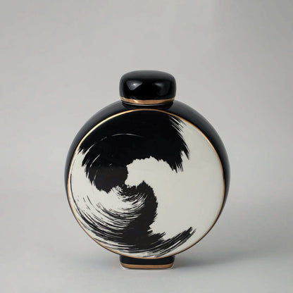 Round ceramic vase in black and beige tones with artistic swirl pattern displayed on white background for interior styling.