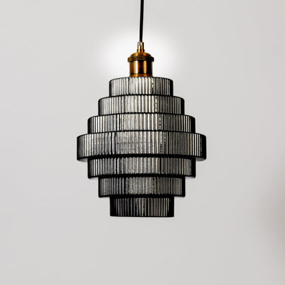 Pendant light with tiered ribbed glass layers shown turned off on a white background highlighting its structured modern form and texture.