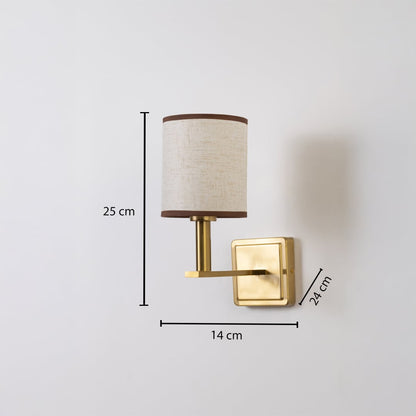 Gold wall sconce with beige drum shade shown with 25 cm height 14 cm width and 24 cm depth for accurate sizing.
