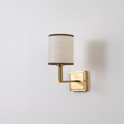 Gold wall sconce with beige drum shade shown switched off on a clean white background for minimal wall decor.