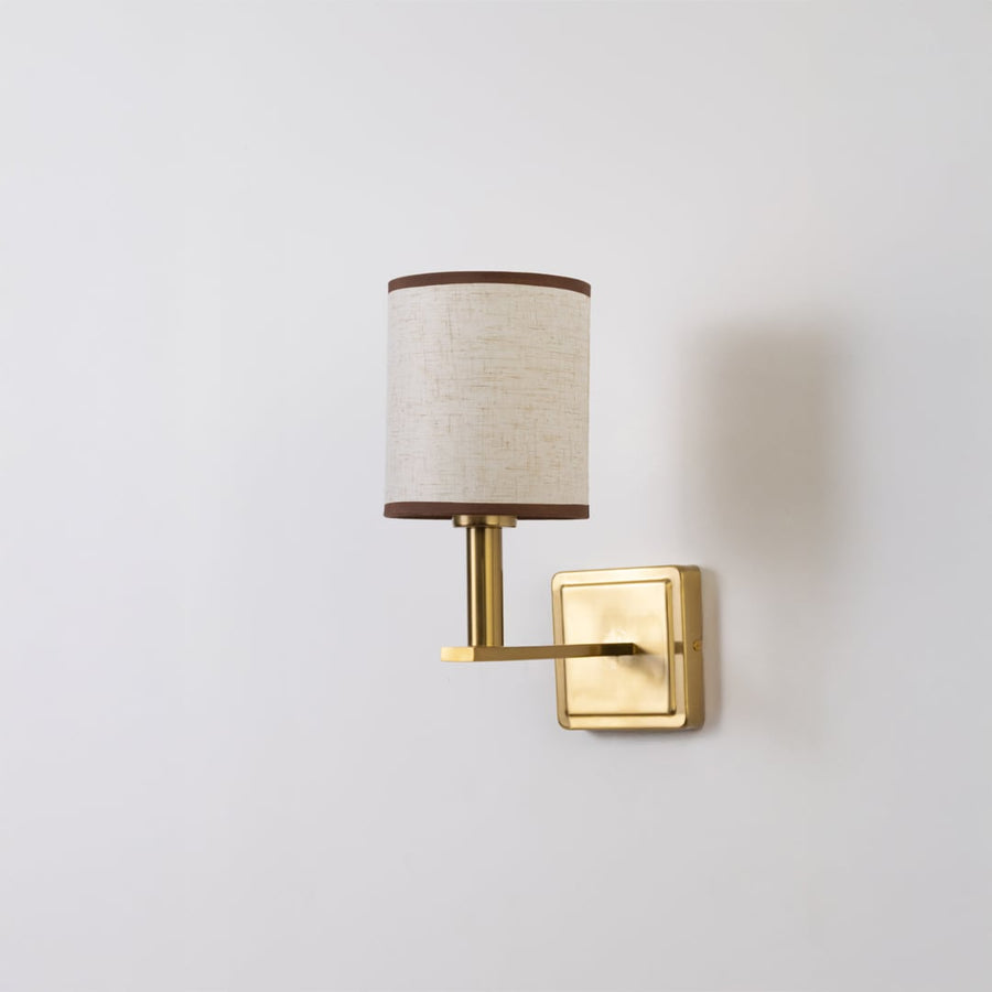 Gold wall sconce with beige drum shade shown switched off on a clean white background for minimal wall decor.