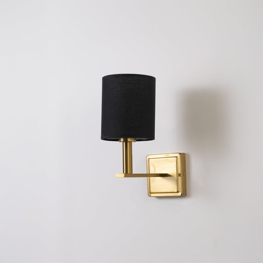 Gold wall sconce with black drum shade shown switched off on a clean white background for minimal wall decor.