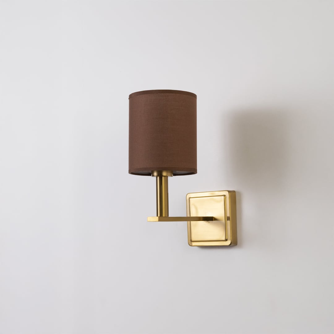 Gold wall sconce with brown drum shade shown switched off on a white background for minimal wall decor.