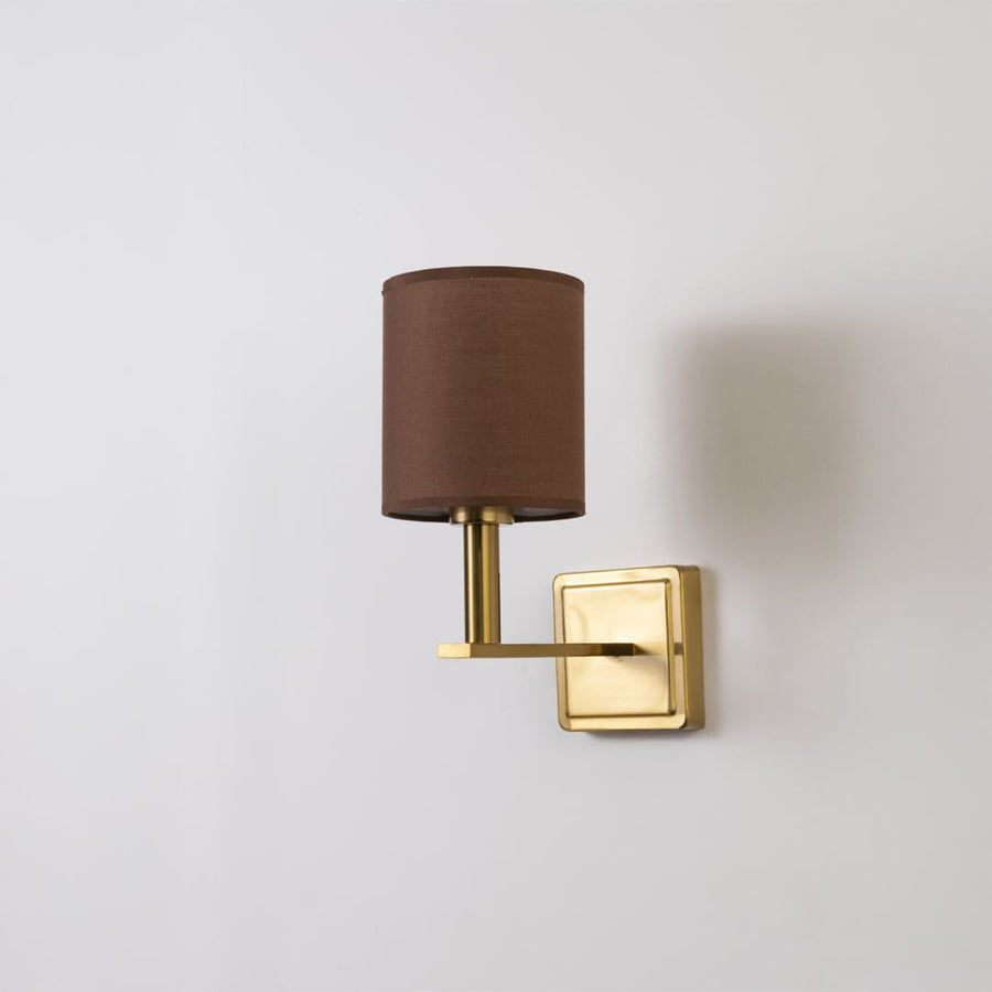 Gold wall sconce with brown drum shade shown switched off on a white background for minimal wall decor.