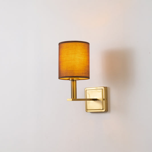 Modern wall light in gold metal finish with fabric shade for bedroom or living room ambient lighting decor white background.