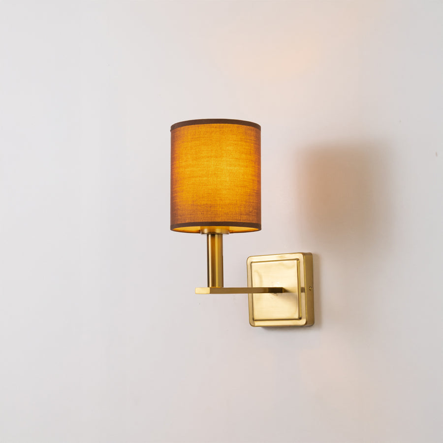 Modern wall light in gold metal finish with fabric shade for bedroom or living room ambient lighting decor white background.